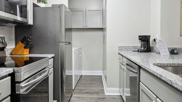 A modern kitchen with stainless steel appliances, a granite countertop, and a wooden floor. - I040 - Cozy 1st Floor 2BD | DFW South | Irving (Irving)