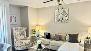 A living room with a sofa, armchair, coffee table, and a ceiling fan. - I040 - Cozy 1st Floor 2BD | DFW South | Irving (Irving)