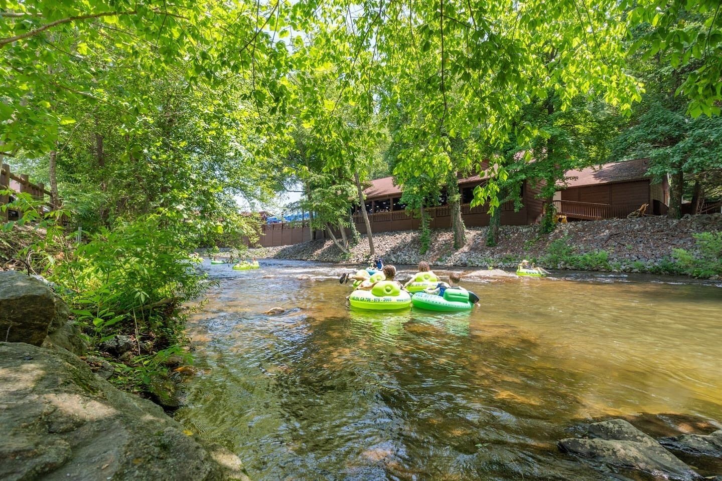 Une rivière où l’on voit des personnes sur des radeaux gonflables verts.