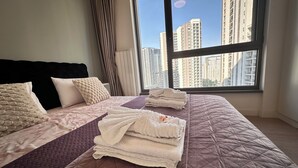 A hotel room with a large bed, a window with a city view, and a radiator. - MILO Lux Apartments 2 - Belgrade
Waterfront - Aqua (Beograd)