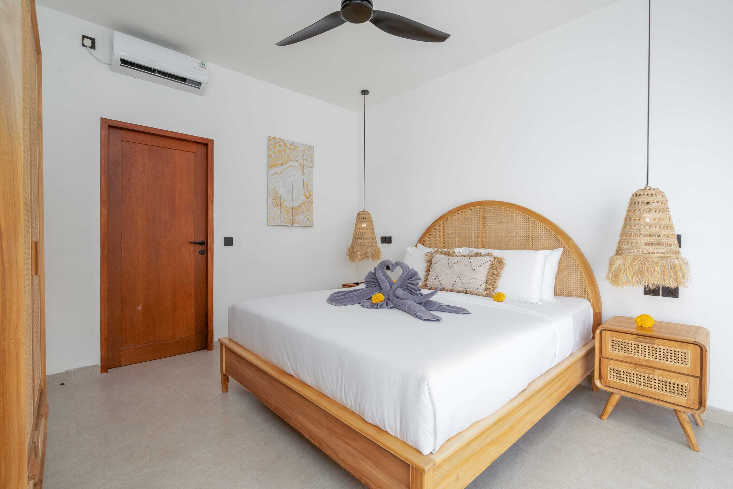 A bedroom with a wooden bed, a ceiling fan, a rattan nightstand, and a wall-mounted air conditioner.