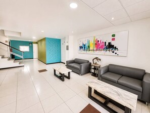 A modern lobby with a staircase, a reception desk, and a seating area with a large abstract painting. - HOTEL PLAZHA (Tuxtla Gutierrez)