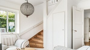 A modern living room with a round wooden table, a white sofa, and a chandelier. - Haveliden by Interhome (Hällevik)