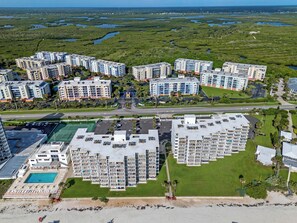 Un complejo residencial de edificios altos con varios balcones, una piscina y una zona de playa.