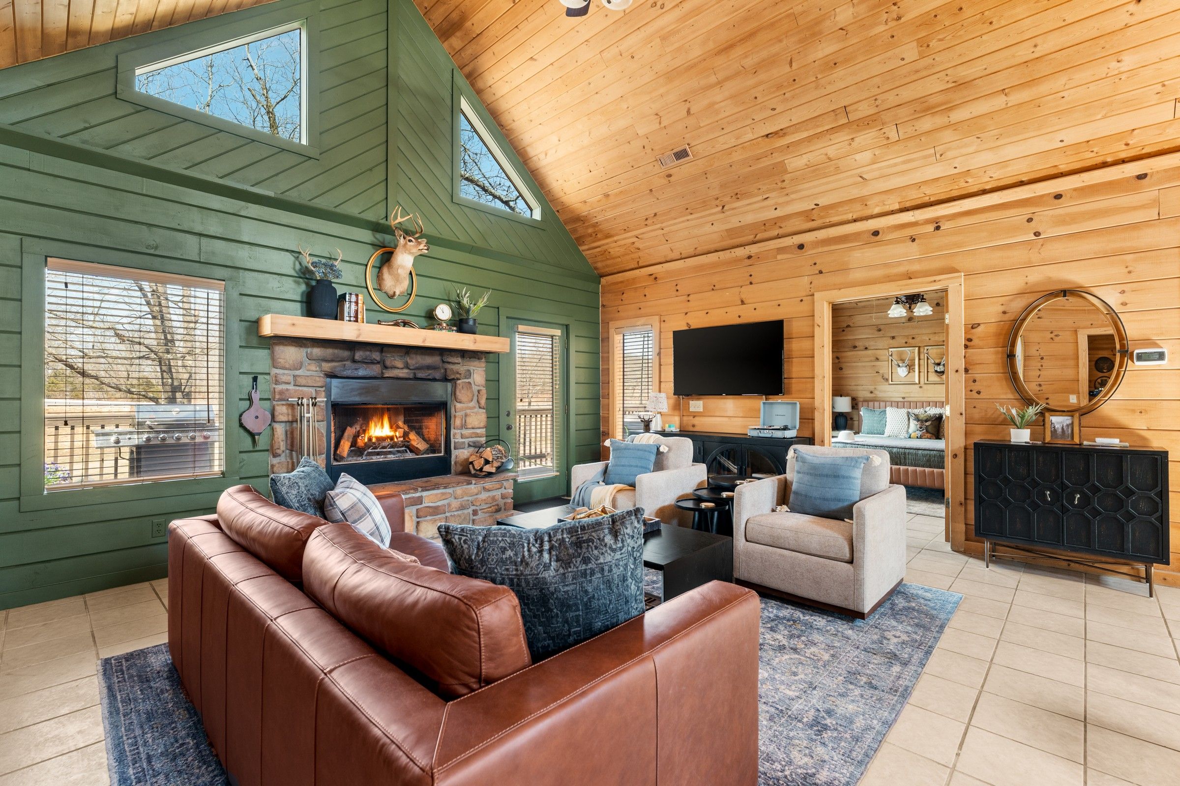 A cozy living room with a stone fireplace, leather sofa, and a television.