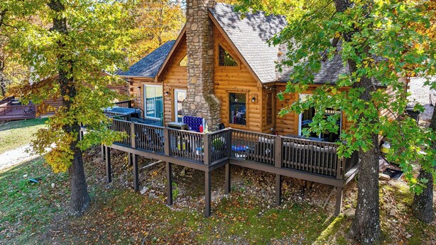A log cabin with a stone chimney, wooden deck, and a covered outdoor seating area. - Luxury Cabin Vibes • Walk to Thunder Ridge (Ridgedale)