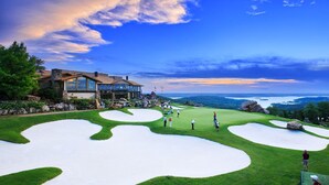 A golf course with a clubhouse, green fairways, sand bunkers, and a scenic view of the surrounding landscape. - Luxury Cabin Vibes • Walk to Thunder Ridge (Ridgedale)