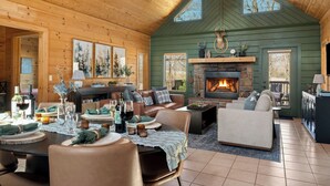 A cozy log cabin interior with a fireplace, wooden walls, and a dining area set for a meal. - Luxury Cabin Vibes • Walk to Thunder Ridge (Ridgedale)