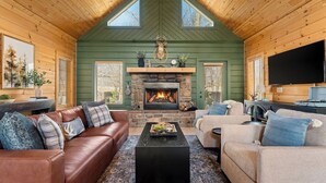 A cozy living room with a stone fireplace, leather sofas, and a flat-screen TV. - Luxury Cabin Vibes • Walk to Thunder Ridge (Ridgedale)