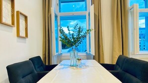Una mesa de comedor con un florero, dos sillas y una ventana con cortinas.