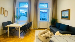 Una habitación con una mesa de comedor, sillas, un sofá, un ventanal con vistas y un cuadro en la pared.