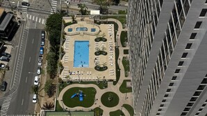 Vue aérienne d’un bâtiment doté d’un court de tennis, d’une piscine et d’un parking.