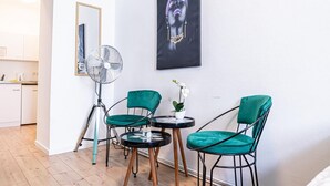 A room with teal chairs, a small round table, a fan, and a painting on the wall. - Chic Cozy Studio, 15 min to City Center (Vienna)