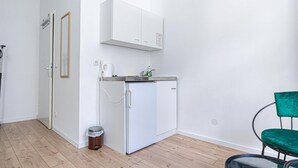 Eine kleine Küche mit Kühlschrank, Arbeitsfläche und Mülleimer.
