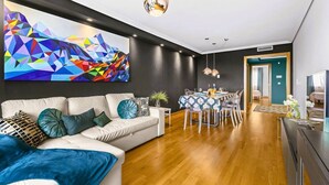 A modern living room with a sofa, dining table, and a colorful abstract painting on the wall. - Eslanzarote Wanderlust house (Arrecife)