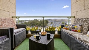 A balcony with wicker furniture, a table with a plate of croissants and two mugs, and potted plants. - Eslanzarote Wanderlust house (Arrecife)