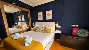 A bedroom with a large bed, a wardrobe, a mirror, and two framed pictures on the wall. - Eslanzarote Wanderlust house (Arrecife)