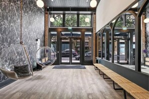 Ein modernes Interieur mit einer hölzernen Bank, einem Hängekorbstuhl und einer Glastür.