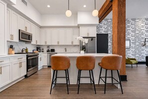 A modern kitchen with white cabinetry, stainless steel appliances, and a central island with bar stools.