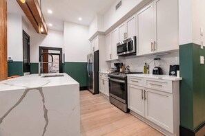 A modern kitchen with white cabinets, stainless steel appliances, and a marble countertop.