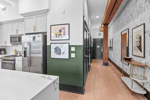 A modern kitchen with stainless steel appliances, framed artwork on the walls, and a wooden floor. - Suite Best Location Walk to Everything Downtown Hotel (New Orleans)