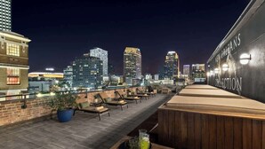 Terraza en la azotea con vistas a la ciudad, sillones de descanso y una zona de bar.