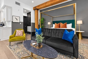 Una sala de estar moderna con un sofá negro, un sillón verde y una mesa de centro.