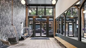 A modern interior with a wooden bench, a hanging chair, and a glass door entrance. - Prime Location King Bed Suite  Gym Rooftop Pool Hotel (New Orleans)