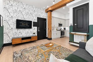 A modern living room with a flat-screen TV, a wooden coffee table, and a patterned rug.