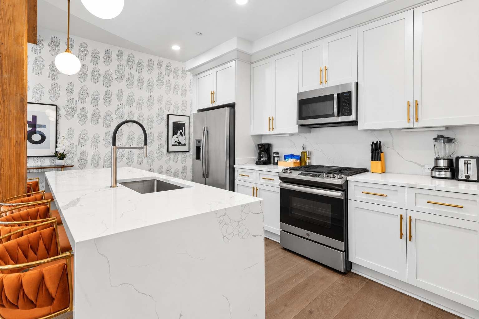 A modern kitchen with white cabinetry, stainless steel appliances, and a marble countertop.
