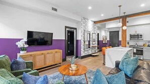 A modern living room with a sofa, a coffee table, and a TV. - Lux 2BR Suite Near Dome and FQ Hotel (New Orleans)