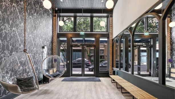 A modern interior with a wooden bench, a hanging chair, and a glass door entrance. - Lux 2BR Suite Near Dome and FQ Hotel (New Orleans)