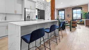 Una cocina moderna con encimera de mármol, electrodomésticos de acero inoxidable y pared de ladrillo.