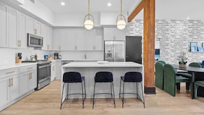 Una cocina moderna con armarios blancos, una isla central y taburetes de bar.