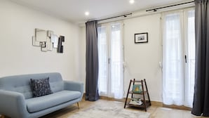 Ein Wohnzimmer mit einem hellblauen Sofa, Holzboden und einer kleinen Holzleiter mit Büchern.