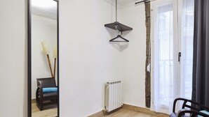 Ein Zimmer mit einem großen Spiegel, einer Heizung, einer Pendelleuchte und einem Sessel.