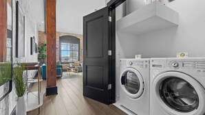 A laundry area with two front-loading washing machines, a black door, and a view of an outdoor seating area.