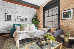 A modern room with a bed, sofa, and a large window. - Prime Location Pool, Style + Lots of Extras Hotel (New Orleans)
