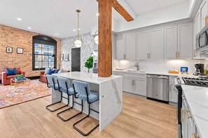 Een moderne keuken met een centraal eiland, grijze kastjes en roestvrijstalen apparatuur.
