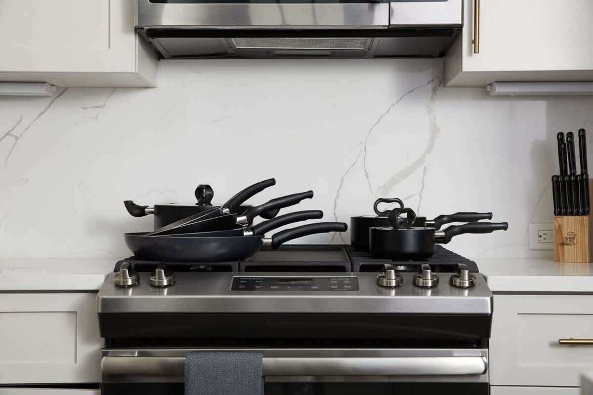 A kitchen with a stainless steel stove, a microwave, and a knife block on the counter.