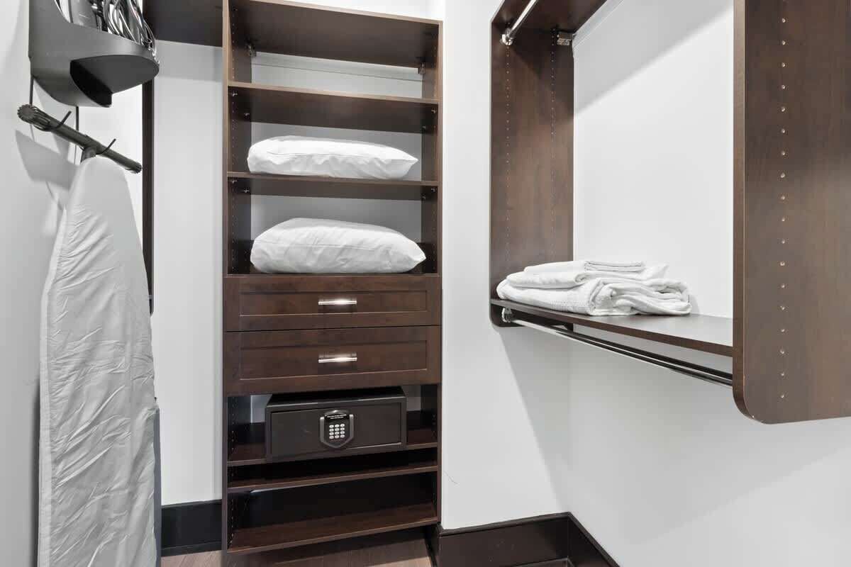 Une chambre d’hôtel équipée d’une armoire intégrée, d’un miroir et d’une étagère où sont pliées des serviettes.