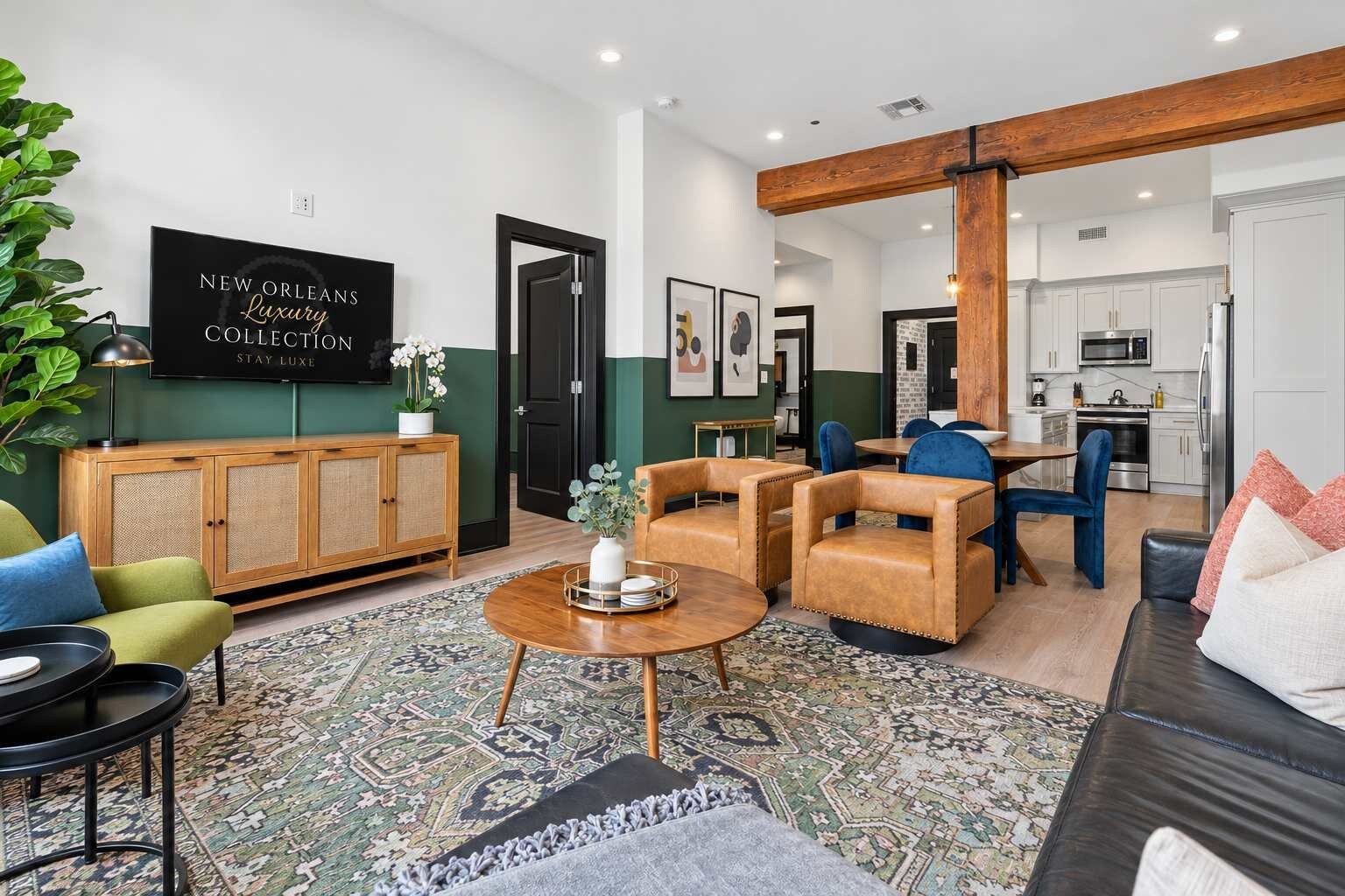 Uma sala de estar moderna com sofá, poltronas, mesa de centro e televisão exibindo 'NEW ORLEANS Luxury Collection Stay Luxe'.