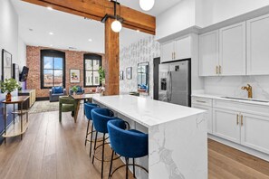 A modern kitchen with white cabinets, a marble countertop, and a stainless steel refrigerator.
