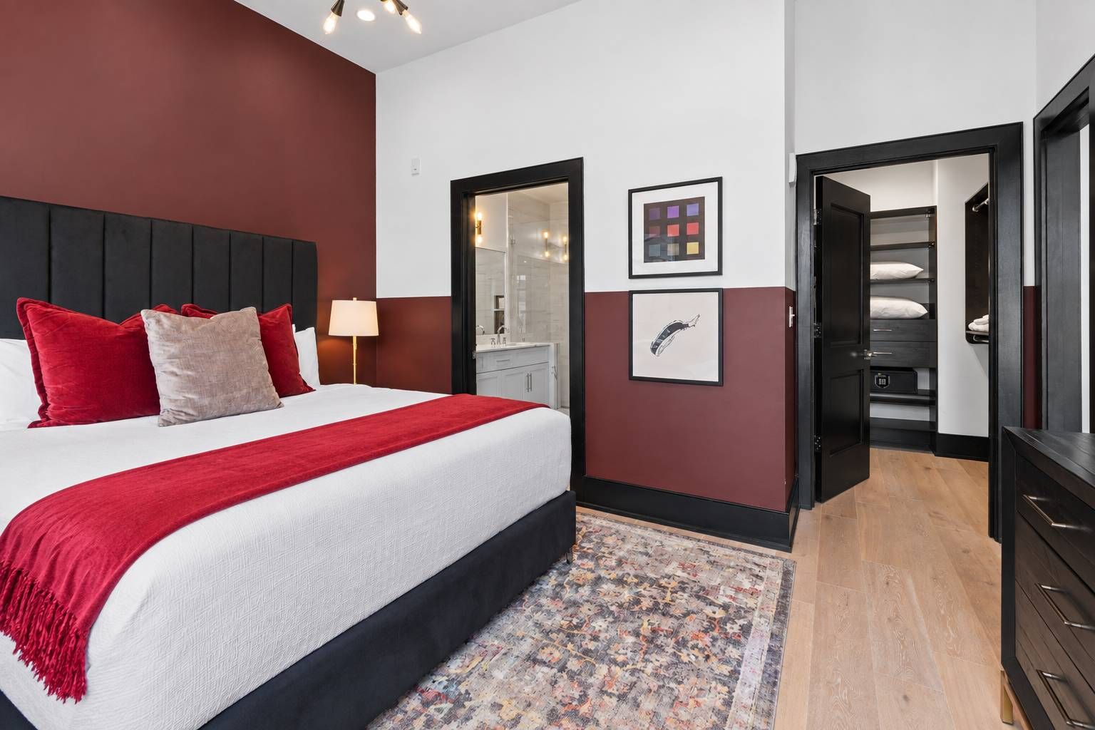 Habitación de hotel con cama, mesita de noche, escritorio, silla, armario y baño visible a través de una puerta.