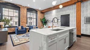 A modern kitchen with a marble island, a built-in dishwasher, and a large window. - Suite Double The Space XL Hotel 2 Living Rooms Kitchens (New Orleans)