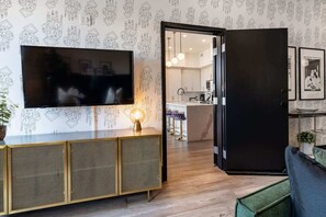 Un salon moderne doté d’un téléviseur à écran plat, d’une console et d’une porte noire donnant sur la cuisine.