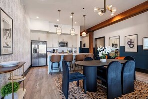 A modern kitchen with stainless steel appliances, a dining area with a round table and chairs, and a patterned rug. - Lux 4BD/4BA +2 Sleeper Sofas | Own Terrace | Hotel (New Orleans)