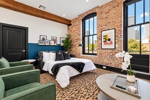 A bedroom with a bed, green armchairs, a coffee table, a plant, and a window with a city view. - Lux 4BD 4BA Suite 2 Sleeper Sofas Own Terrace Hotel (New Orleans)