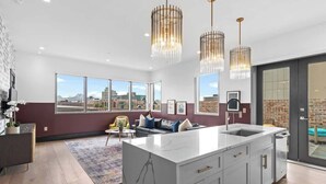 A modern kitchen with a large island, pendant lights, and a view of the cityscape. - Downtown Corner Penthouse w Private Terrace Suite Hotel (New Orleans)