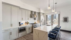 Una cocina moderna con armarios blancos, electrodomésticos de acero inoxidable y una isla de mármol.